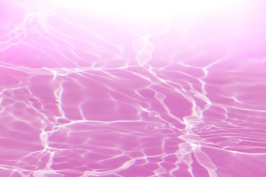 Defocus bulanık, şeffaf pembe, berrak, durgun su yüzeyi dokusu, sıçrama ve kabarcıklarla bulanıklaştırılmış. Moda soyut doğa geçmişi. Güneş ışığıyla birlikte su dalgaları. Pembe su parlıyor 