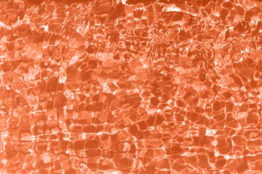 Defocus blurred transparent orange colored clear calm water surface texture with splashes and bubbles. Trendy abstract nature background. Water waves in sunlight with caustics. Orange water shinning