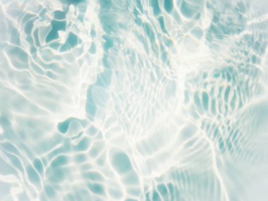 Defocus blurred transparent blue colored clear calm water surface texture with splashes and bubbles. Trendy abstract nature background. Water waves in sunlight with copy space. Blue water shine