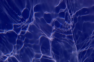 Defocus blurred transparent blue colored clear calm water surface texture with splashes and bubbles. Trendy abstract nature background. Water waves in sunlight with copy space. Blue water shine