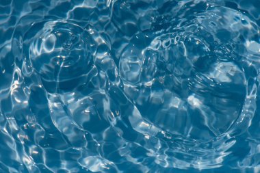 Defocus blurred transparent blue colored clear calm water surface texture with splashes and bubbles. Trendy abstract nature background. Water waves in sunlight with copy space. Blue water shine
