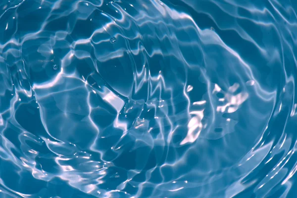 焦点がぼやけた透明ブルーの透明感のある透明感のある穏やかな水面の質感とスプラッシュと泡 傾向の抽象的な性質の背景 コピースペースと日光の水の波 青い水の輝き — ストック写真