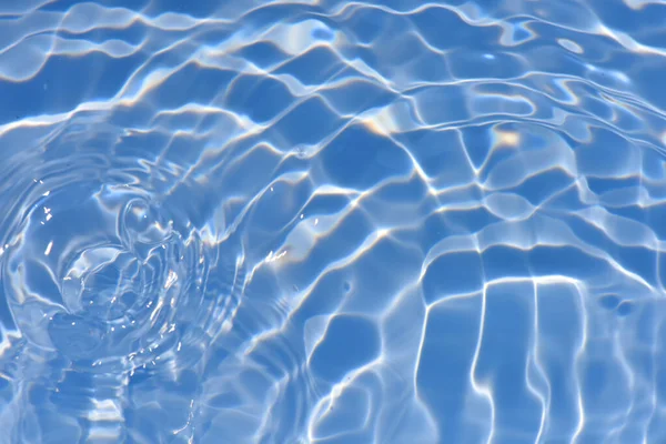 焦点がぼやけた透明ブルーの透明感のある透明感のある穏やかな水面の質感とスプラッシュと泡 傾向の抽象的な性質の背景 コピースペースと日光の水の波 青い水の輝き — ストック写真