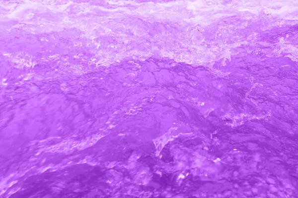 表面に波紋を持つ紫色の水 焦点がぼやけた透明ブルーの透明感のある透明感のある穏やかな水面の質感とスプラッシュと泡 輝くパターンの質感の背景を持つ水の波 — ストック写真
