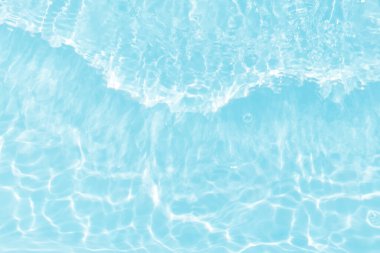 Yüzeyinde dalgalanmalar olan mavi su. Defocus bulanık mavi şeffaf, berrak, durgun su yüzeyi dokusu sıçrama ve kabarcıklarla bulanıklaştırılmış. Parlak desenli arka planda su dalgaları.