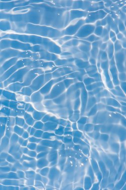 Yüzeyinde dalgalanmalar olan mavi su. Defocus bulanık mavi şeffaf, berrak, durgun su yüzeyi dokusu sıçrama ve kabarcıklarla bulanıklaştırılmış. Parlak desenli arka planda su dalgaları.