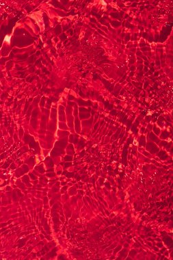 Yüzeyinde dalgalanmalar olan turuncu su. Defocus bulanık, şeffaf pembe, berrak, durgun su yüzeyi dokusu, sıçrama ve kabarcıklarla bulanıklaştırılmış. Parlak desenli arka planda su dalgaları.