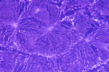 Yüzeyinde dalgalanmalar olan mor bir su. Defocus bulanık, şeffaf pembe, berrak, durgun su yüzeyi dokusu, sıçrama ve kabarcıklarla bulanıklaştırılmış. Parlak desenli arka planda su dalgaları.