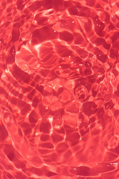 stock image Orange water with ripples on the surface. Defocus blurred transparent pink colored clear calm water surface texture with splashes and bubbles. Water waves with shining pattern texture background.