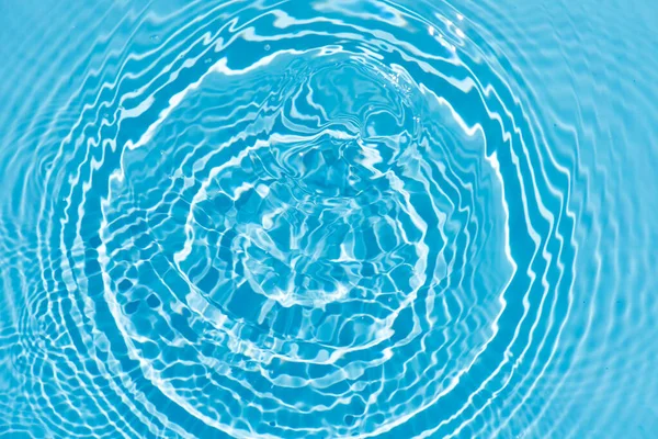 水面上有波纹的蓝色水 Defocus模糊了透明的蓝色清晰平静的水面纹理与水花和气泡 具有闪光图案纹理背景的水波 图库照片