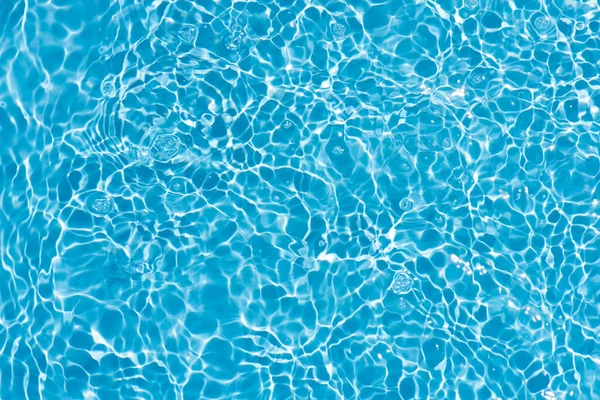 水面上有波纹的蓝色水 Defocus模糊了透明的蓝色清晰平静的水面纹理与水花和气泡 具有闪光图案纹理背景的水波 免版税图库图片