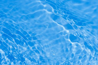 Yüzeyde mavi su kabarcıkları. Defocus bulanık, şeffaf, beyaz-siyah, berrak, durgun su yüzeyi dokusu, sıçrama ve kabarcıklarla bulanıklaşmış. Parlak desenli arka planda su dalgaları.