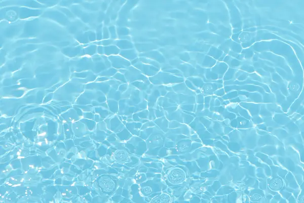 Defocus模糊了透明的蓝色清晰平静的水面纹理与水花和气泡 潮流抽象的自然背景 阳光下的水波有复制空间 蓝色水彩斑斓 图库图片