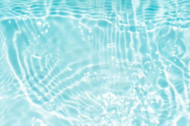 Yüzeydeki mavi su dalgaları bulanıklaştı. Defocus bulanık mavi şeffaf, berrak, durgun su yüzeyi dokusu sıçrama ve kabarcıklarla bulanıklaştırılmış. Parlak desenli arka planda su dalgaları.