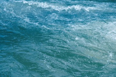 Defocus bulanık mavi şeffaf, berrak, durgun su yüzeyi dokusu sıçrama ve kabarcıklarla bulanıklaştırılmış. Moda soyut doğa geçmişi. Güneş ışığında fotokopi uzayıyla birlikte su dalgaları. Mavi suluboya parlıyor