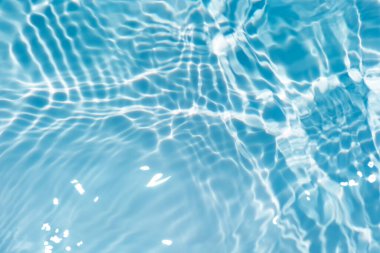 Defocus bulanık mavi şeffaf, berrak, durgun su yüzeyi dokusu sıçrama ve kabarcıklarla bulanıklaştırılmış. Moda soyut doğa geçmişi. Güneş ışığında fotokopi uzayıyla birlikte su dalgaları. Mavi suluboya parlıyor