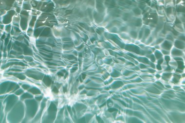 Yüzeydeki mavi su dalgaları bulanıklaştı. Defocus bulanık mavi şeffaf, berrak, durgun su yüzeyi dokusu sıçrama ve kabarcıklarla bulanıklaştırılmış. Parlak desenli arka planda su dalgaları.