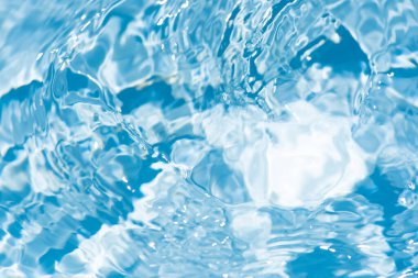 Yüzeydeki mavi su dalgaları bulanıklaştı. Defocus bulanık mavi şeffaf, berrak, durgun su yüzeyi dokusu sıçrama ve kabarcıklarla bulanıklaştırılmış. Parlak desenli arka planda su dalgaları.