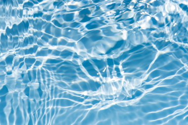 Yüzeydeki mavi su dalgaları bulanıklaştı. Defocus bulanık mavi şeffaf, berrak, durgun su yüzeyi dokusu sıçrama ve kabarcıklarla bulanıklaştırılmış. Parlak desenli arka planda su dalgaları.