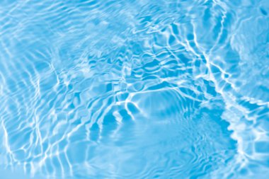 Su yüzeyi. Yüzeydeki mavi su dalgaları bulanıklaştı. Defocus bulanık mavi şeffaf, berrak, durgun su yüzeyi dokusu sıçrama ve kabarcıklarla bulanıklaştırılmış. Parlak desenli su dalgaları.