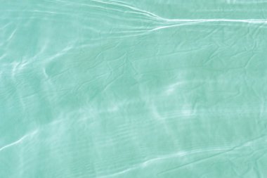 Yüzeydeki mavi su dalgaları bulanıklaştı. Defocus bulanık mavi şeffaf, berrak, durgun su yüzeyi dokusu sıçrama ve kabarcıklarla bulanıklaştırılmış. Parlak desenli arka planda su dalgaları.