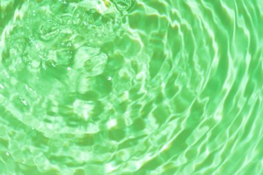 Yüzeydeki mavi su dalgaları bulanıklaştı. Defocus bulanık mavi şeffaf, berrak, durgun su yüzeyi dokusu sıçrama ve kabarcıklarla bulanıklaştırılmış. Parlak desenli arka planda su dalgaları.