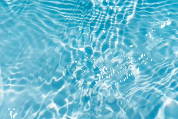 Yüzeydeki mavi su dalgaları bulanıklaştı. Defocus bulanık mavi şeffaf, berrak, durgun su yüzeyi dokusu sıçrama ve kabarcıklarla bulanıklaştırılmış. Parlak desenli arka planda su dalgaları.