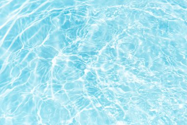 Yüzeydeki mavi su dalgaları bulanıklaştı. Defocus bulanık mavi şeffaf, berrak, durgun su yüzeyi dokusu sıçrama ve kabarcıklarla bulanıklaştırılmış. Parlak desenli arka planda su dalgaları.