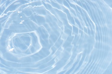 Yüzeydeki mavi su dalgaları bulanıklaştı. Defocus bulanık mavi şeffaf, berrak, durgun su yüzeyi dokusu sıçrama ve kabarcıklarla bulanıklaştırılmış. Parlak desenli arka planda su dalgaları.