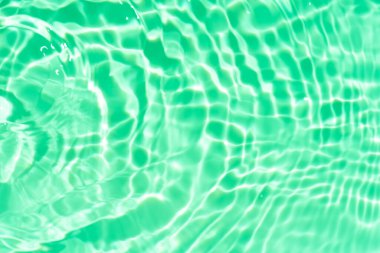 Yüzeydeki mavi su dalgaları bulanıklaştı. Defocus bulanık mavi şeffaf, berrak, durgun su yüzeyi dokusu sıçrama ve kabarcıklarla bulanıklaştırılmış. Parlak desenli arka planda su dalgaları.