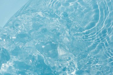 Yüzeydeki mavi su dalgaları bulanıklaştı. Defocus bulanık mavi şeffaf, berrak, durgun su yüzeyi dokusu sıçrama ve kabarcıklarla bulanıklaştırılmış. Parlak desenli arka planda su dalgaları.