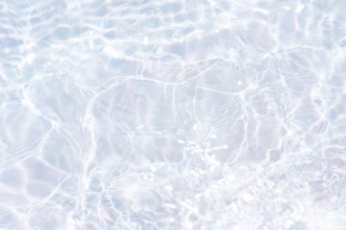 Yüzeyinde dalgalanmalar olan mavi su. Defocus bulanık mavi şeffaf, berrak, durgun su yüzeyi dokusu sıçrama ve kabarcıklarla bulanıklaştırılmış. Parlak desenli arka planda su dalgaları.