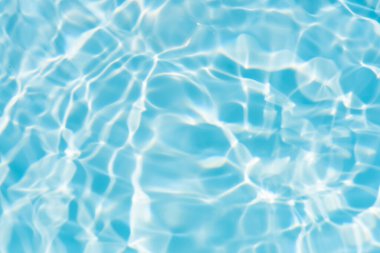 Yüzeyinde dalgalanmalar olan mavi su. Defocus bulanık mavi şeffaf, berrak, durgun su yüzeyi dokusu sıçrama ve kabarcıklarla bulanıklaştırılmış. Parlak desenli arka planda su dalgaları.