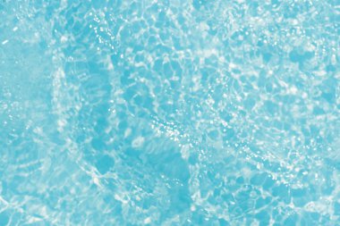 Yüzeydeki mavi su dalgaları bulanıklaştı. Defocus bulanık mavi şeffaf, berrak, durgun su yüzeyi dokusu sıçrama ve kabarcıklarla bulanıklaştırılmış. Parlak desenli arka planda su dalgaları.