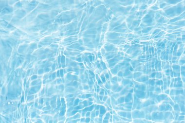 Yüzeydeki mavi su dalgaları bulanıklaştı. Defocus bulanık mavi şeffaf, berrak, durgun su yüzeyi dokusu sıçrama ve kabarcıklarla bulanıklaştırılmış. Parlak desenli arka planda su dalgaları.