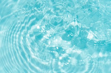 Yüzeydeki mavi su dalgaları bulanıklaştı. Defocus bulanık mavi şeffaf, berrak, durgun su yüzeyi dokusu sıçrama ve kabarcıklarla bulanıklaştırılmış. Parlak desenli arka planda su dalgaları.