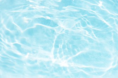 Yüzeydeki mavi su dalgaları bulanıklaştı. Defocus bulanık mavi şeffaf, berrak, durgun su yüzeyi dokusu sıçrama ve kabarcıklarla bulanıklaştırılmış. Parlak desenli arka planda su dalgaları.