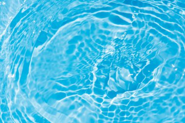 Yüzeydeki mavi su dalgaları bulanıklaştı. Defocus bulanık mavi şeffaf, berrak, durgun su yüzeyi dokusu sıçrama ve kabarcıklarla bulanıklaştırılmış. Parlak desenli arka planda su dalgaları.