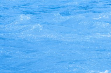 Yüzeydeki mavi su dalgaları bulanıklaştı. Defocus bulanık mavi şeffaf, berrak, durgun su yüzeyi dokusu sıçrama ve kabarcıklarla bulanıklaştırılmış. Parlak desenli arka planda su dalgaları.