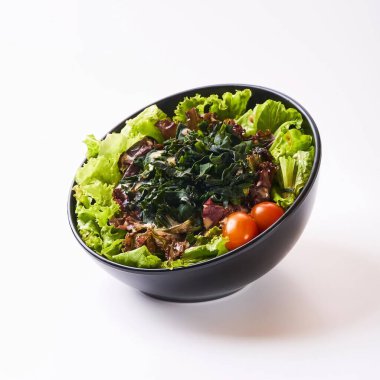 Close up healthy vegetables in black bowl isolated on white background. Healthy food concept