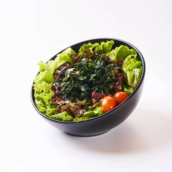 Close up healthy vegetables in black bowl isolated on white background. Healthy food concept