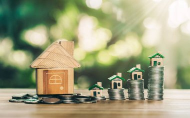 Para ve sikkelerin üzerine yerleştirilen ev ahşap masanın üzerine yerleştirilen merdiven. gayrımenkul merdiveni, ipotek ve emlak yatırımları için konsept satın almak amacıyla madeni paralardan tasarruf parası planlamak.