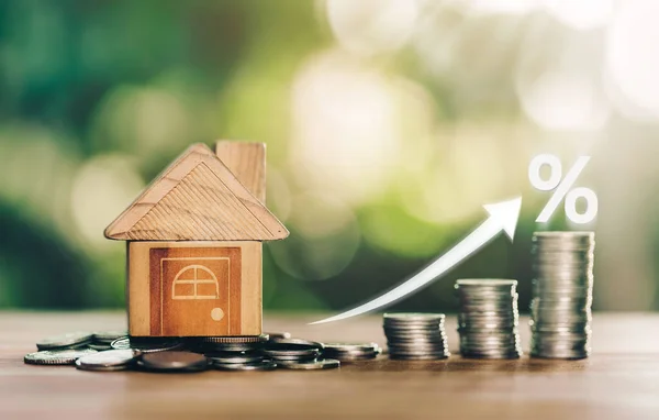 Ev, madeni paraların üzerine istiflenmiş paraların üzerine yerleştiriliyor ve beyaz çizimler faiz oranlarının arttığını gösteriyor. Faiz ödemelerini hesaplama kavramı. gayrımenkul ve ipotek için konsept satın almak için madeni paralardan tasarruf parası planlamak.