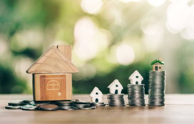 Para ve sikkelerin üzerine yerleştirilen ev ahşap masanın üzerine yerleştirilen merdiven. gayrımenkul merdiveni, ipotek ve emlak yatırımları için konsept satın almak amacıyla madeni paralardan tasarruf parası planlamak.