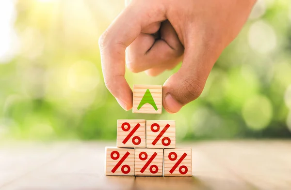 Interest rate financial and mortgage rates concept. Hand putting wood cube block increasing on top with icon percentage symbol upward direction. business concept of investment interest rates appraisal