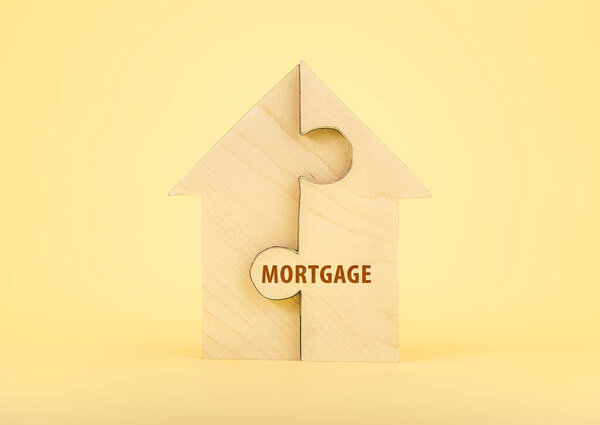 Деревянная головоломка Напишите слово "ипотека" ждать, чтобы выполнить домашнюю форму для строительства дома мечты. Счастливая жизнь. планирование сбережения концепции дома для инвестиций в недвижимость, ипотеку и недвижимость для дома.