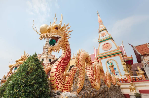 A giant golden Chinese dragon that holds a green glass ball. Located in Wat Phra Thaen Temple, Thailand, Udon Thani Province.