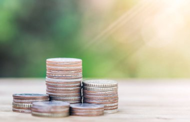 Tahta bir masaya yerleştirilen paralar çeşitli fonların yerleştirilmesi için gerekli parayı gösteriyor. Gayrimenkul, ipotek ve gayrimenkul yatırımları için konsept satın almak amacıyla madeni paralardan tasarruf parası planlıyorlar. bir ev için tasarruf