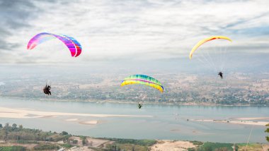 Gökyüzünde paraşütle atlıyor. Paraglider, Tayland 'ın Nongkhai kentindeki Wat Pha Tak Suea' daki Güzel Görüş Mekong Nehri 'nden manzara üzerinde uçuyor. Ekstrem spor kavramı, macera / meydan okuma.