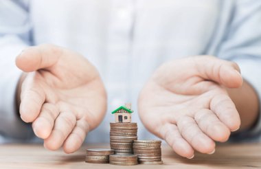 Evi ve sikkeyi veren kişinin eli bu. Emlak, yatırım, ev satın alma konsepti. Mülk, ipotek ve yatırım konsepti. Ev almak için tasarruf.